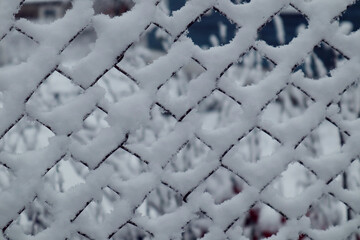 Metal mesh covered with fluffy snow, side view, close-up
