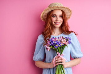 woman in blue dress enjoy flowers, posing isolated on pink background, smiling