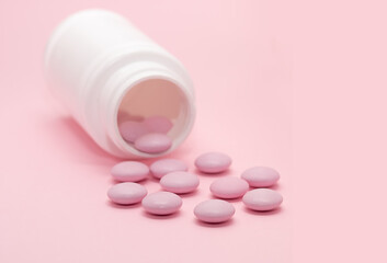 Pills on a pink background in a bottle. Medicine and vitamins. From the disease.