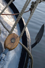 White painted metal pulley on a ship. Focus on the edge of the pulley and rope