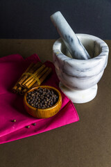 Black peppercorns, cinnamon sticks, pestle and mortar.