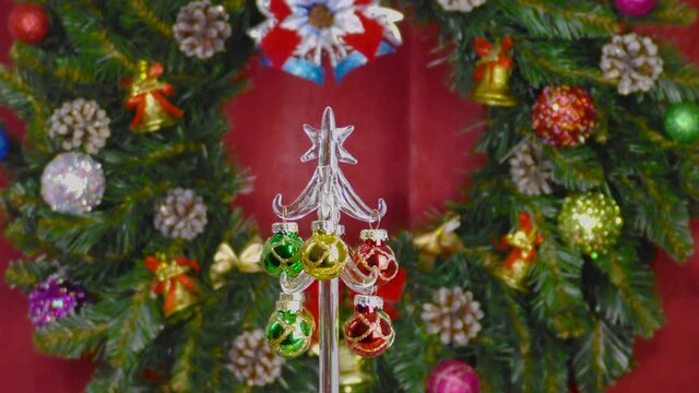 Against the background of a Christmas wreath on a red cloth, a small Christmas tree stands on a gift