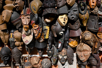African old wooden masks of different sizes are hanging for sale. Colorful scary masks are sold on...