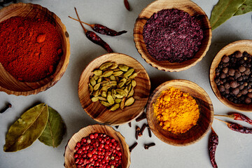 Сlose view of various colorful spices in wood bowls on concrete background. Top view with copy...
