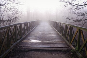 Fototapeta na wymiar Foggy old rotten wooden bridge in winter morning in Budapest suburb, Hungary