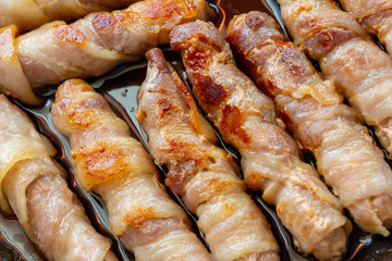 Cooked sausages in bacon. bacon roll close up. Abstract background with bacon.