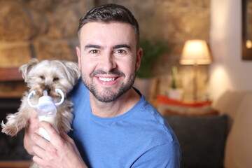Man holding small dog and feeding bottle