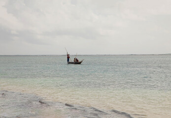 unrecognizable three Kenyan fishermen in the distance in a boat with a long oar went fishing
