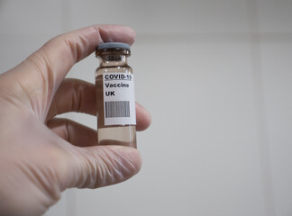 Covid-19 vaccine hold by a glove hand with UK label
