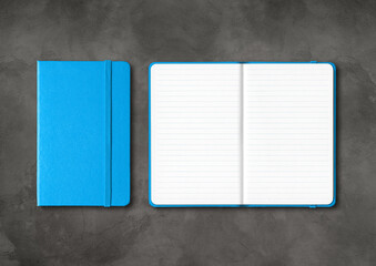 Blue closed and open lined notebooks on dark concrete background