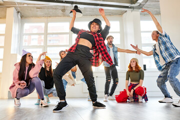 hip hop dancer in motion, showing movements for people surrounding dancer in studio, talented and flexible