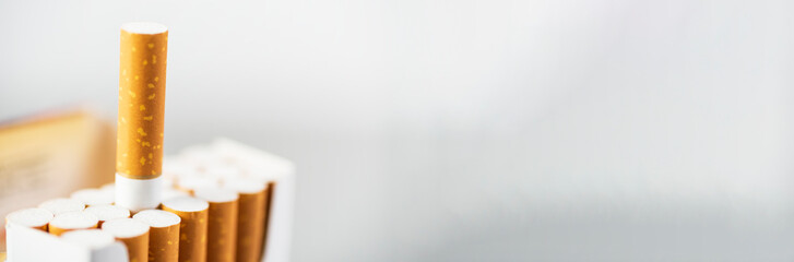 Open pack of cigarettes with one outstretched cigarette close up, place for text, banner