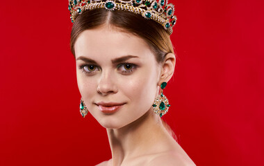 Portrait of a beautiful woman with a diadem on her head on a red background