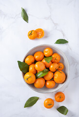 sweet and juicy tangerines in a ceramic  bowl  on a white marble background.