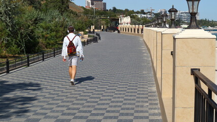 
Odessa embankment, along which a man in headphones with a bottle of water in his hand and a backpack on his shoulders is walking