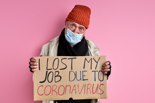 Homeless Man In Mask Lost His Job Due To Coronavirus COVID-19, He Stands With Cardboard, Need Shelter And Food, Isolated In Studio