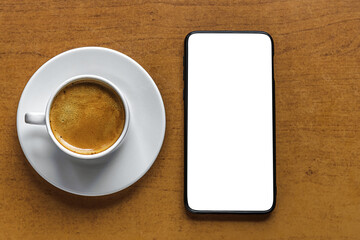 Fototapeta na wymiar aromatic freshly brewed coffee in a white porcelain cup and smartphone on a table, mock up, flat lay