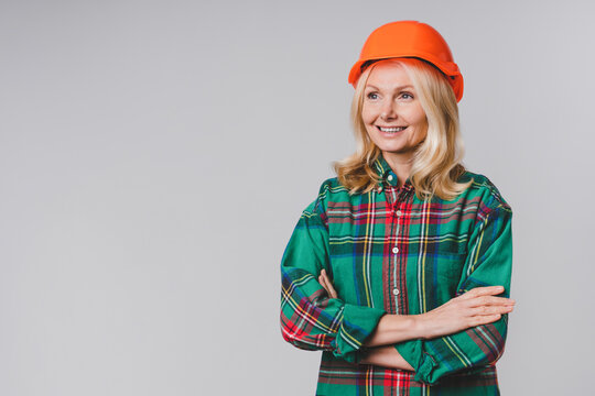 Middle-aged Beautiful Woman Construction Worker In Hard Hat With Arms Crossed Isolated Over Grey Background