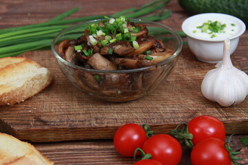 bowl with fried mushrooms and green onions on a wooden table