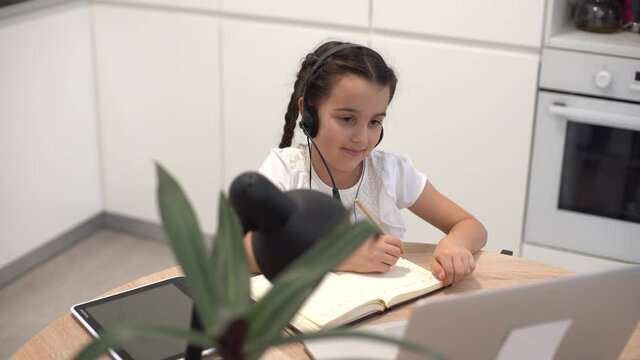 Little girl kid studen studying online class with laptop at home, New normal. Covid-19 coronavirus. Social distancing, home schooling.
