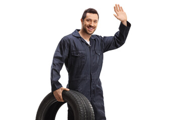 Auto mechanic holding a vehicle tire and waving