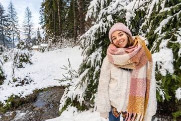 Young woman at winter. Winter holidays concept. Girl outdoors. Gilr wearingknitted hat walking in winter park and enjoying the snow.