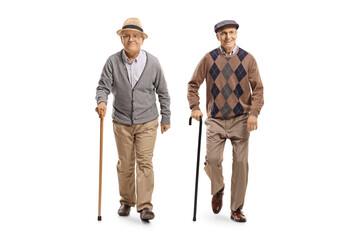 Full length portrait of two elderly men with canes walking towards camera