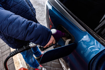 Hand refilling the car with fuel at the refuel station.