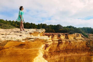 one beautiful sexy girl stands on stones on a rock in Portugal. a woman on a cliff stands on the edge.