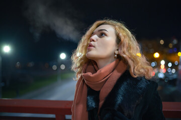 Cute woman breathing vapour at the winter