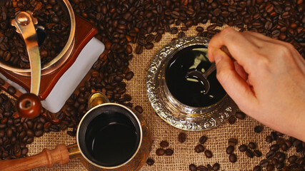 Woman hand stirring coffee in cup.