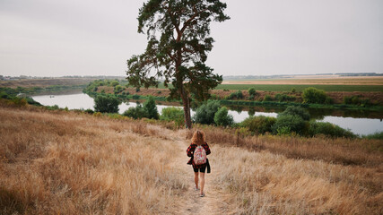 The girl who walks to the tree in the autumn. Against the background of the river