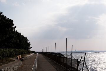 Fototapeta na wymiar Path and bench along the quay in Isshiki, Nishio City, Aichi Prefecture, under clear skies.