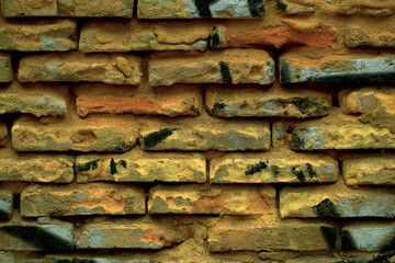 Rough weathered brick wall background texture with exposed damaged long narrow bricks in a full frame view. This is a lighter version, a darker version is also available in the portfolio