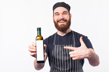 Smiling Barista man pointing at best olive oil bottle.