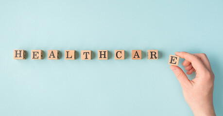 Healthcare concept. Pov close up view photo of female hand putting last wooden block in a line making word healthcare isolated pastel color backdrop