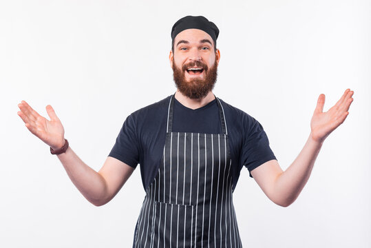 Photo of cheerful Chef man with beard making welcome gesture.