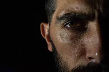 medio rostro con una mirada directa a la cámara en un fondo negro 