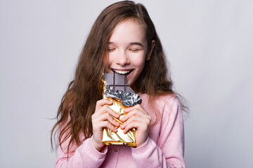 Close up portrait of cute girl eating Chocolate over grey background and smile.