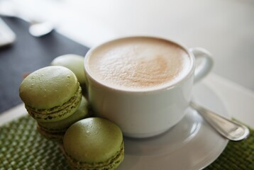 a cup of coffee and pistachio macarons