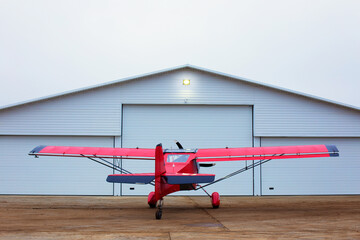 Small single prop engine aircrafts planes parked inside workshop hangar with closed door. Private...