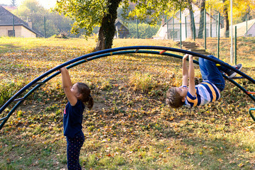 Carefree kids having fun while hanging on monkey bars at the playground.