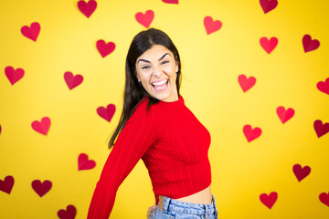 Young caucasian woman over yellow background with red hearts shouting, holidays concept.