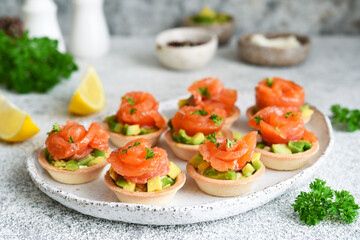 Tartlets with cream cheese, avocado and salmon. Salmon appetizer on the kitchen table.