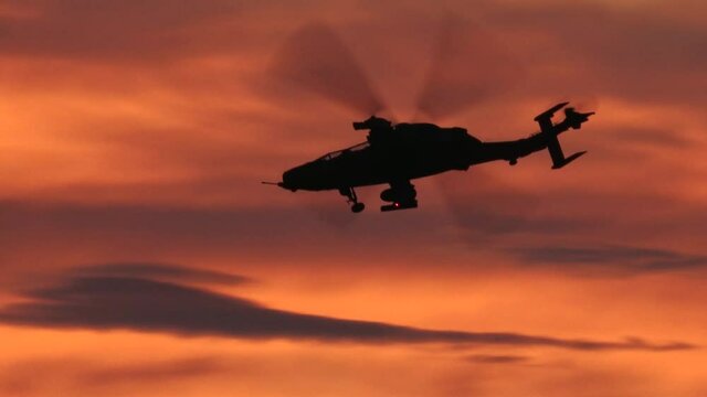 Attack helicopter flying at sunset