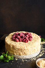 Homemade  Napoleon cake with cream and raspberries on a dark concrete background. Vertical focus.