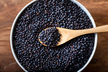 Beluga. Black lentil in scoop on wooden background.