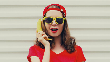 Portrait of funny woman calling on a banana phone on a white background