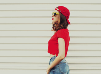 Portrait of young woman wearing a red baseball cap looking away on a white background