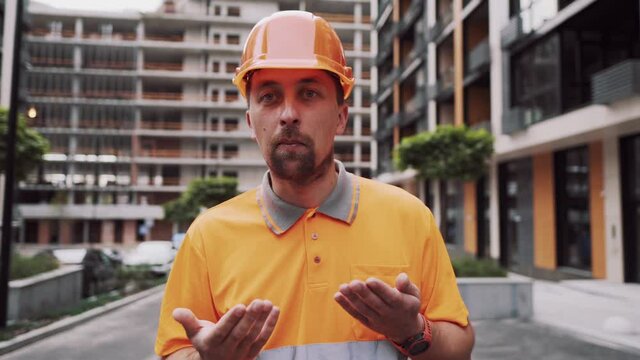 Caucasian male construction manager angry and displeased wearing construction orange clothes and hard hat. The foreman is annoyed by the delay in construction. Builder emotionally rage